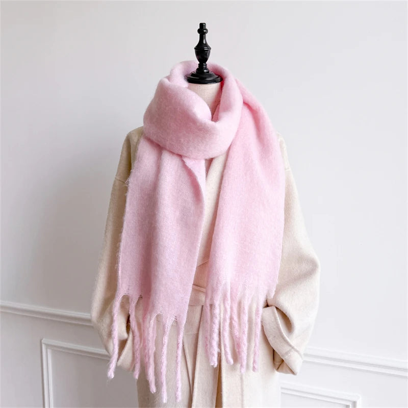 Ein weicher Pastellrosa-Wollschal für Damen mit Cashmere-ähnlichem Gefühl für den Winter mit gefransten Kanten, drapiert um eine Schaufensterpuppe.