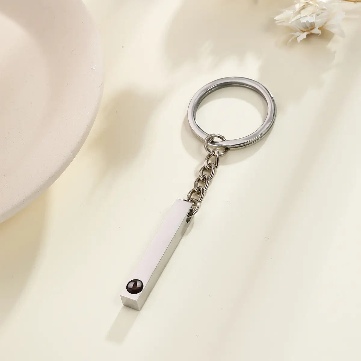 Silver rectangular custom photo projection keychain with a polished metallic finish and a small black spherical accent personalized as a memorial gift.