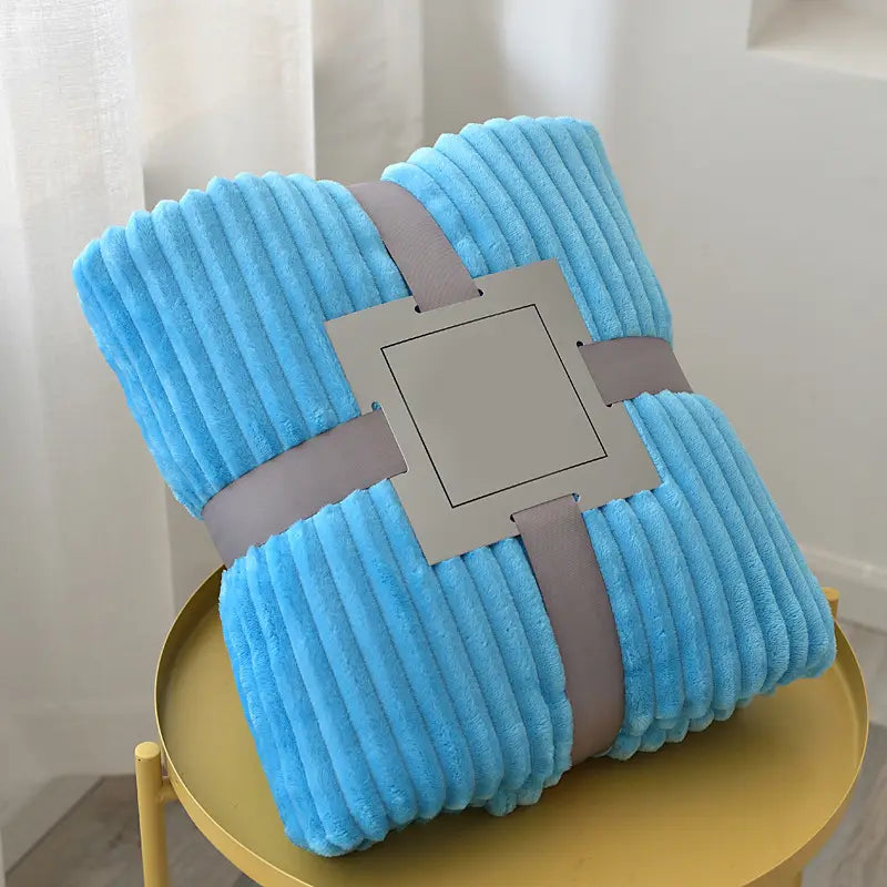 Hellblaue Fleecedecke 100x150 cm aus weichem Corduroy-Fleece, ordentlich mit einem grauen Band umwickelt, geeignet für Bett oder Sofa