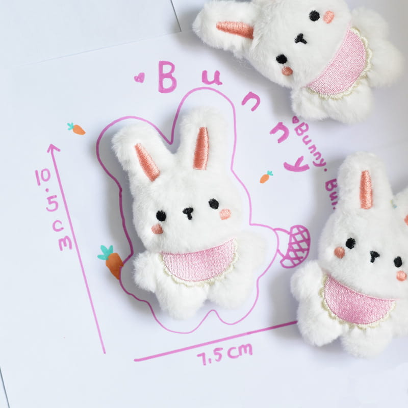 ピンクの刺繍アクセントと、ピーチ色の耳が付いた、インタラクティブなかわいい動物の笛（スウィーカー）犬用おもちゃの白いふわふわウサギのチャームです。