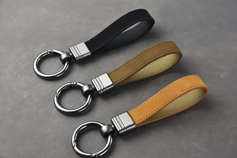 Leather keychains set with multicolor metal clasp featuring black tan and orange leather rectangular connectors and metal rings.