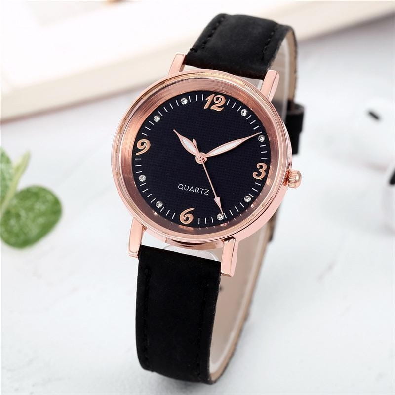 Women quartz watch with a rose gold dial, black leather band, and diamond accents on the bezel and hour markers.