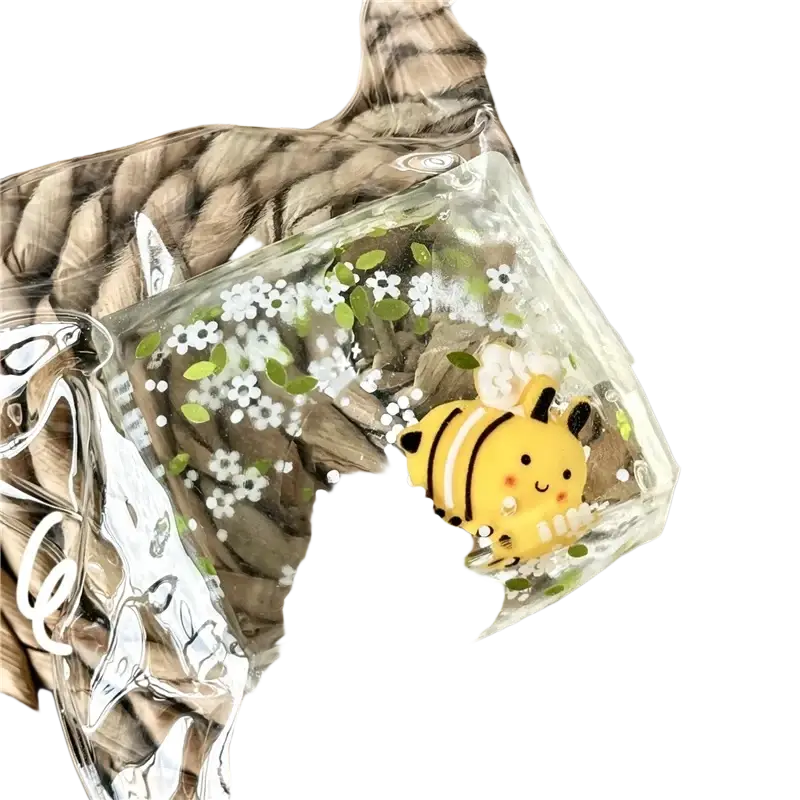 A yellow and black bee figurine inside a clear resin cube filled with white flowers in a slow rebound fidget toy