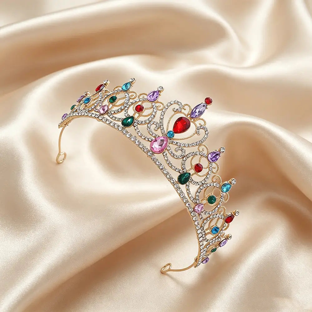 Une couronne de diadème baroque en strass doré étincelante, ornée de cristaux colorés rouges, verts, bleus, violets et roses, disposés dans un filigrane complexe pour accessoire de coiffure de mariée.