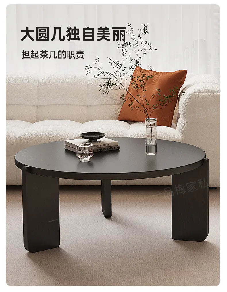 Moderner schwarzer runder Couchtisch mit massiven, blockigen Beinen, die ein solides Design erkennen lassen; ideal für zeitgemäße Wohnbereiche und Verkaufsargumente.