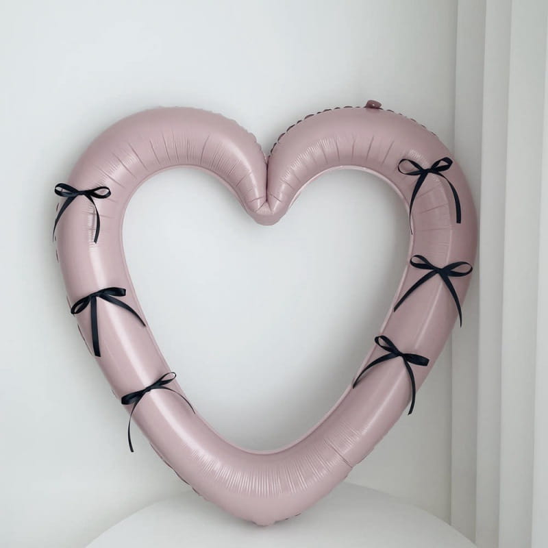 Un globo de lámina para marco de foto de corazón de 40 pulgadas en color rosa con forma de corona y adornado con cintas negras