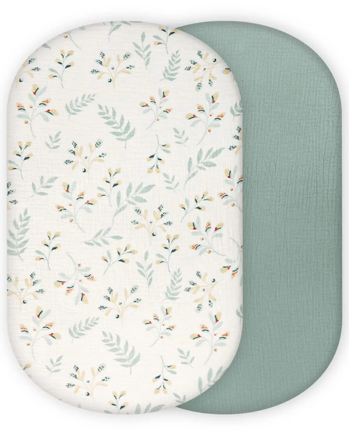 ein Babybettlaken-Set aus Baumwollmuslin mit einer weichen ovalen Wickelunterlage mit zartem botanischem Druck auf einer Seite und einfarbigem Salbeigrün auf der Rückseite.