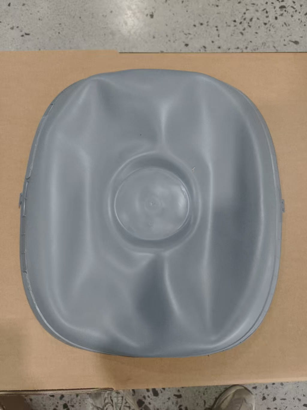 couvercle en plastique gris légèrement texturé avec une indentation circulaire centrale et des bords arrondis, pour la plaque de silicone de remplacement utilisée dans la boîte à litière pour chat.