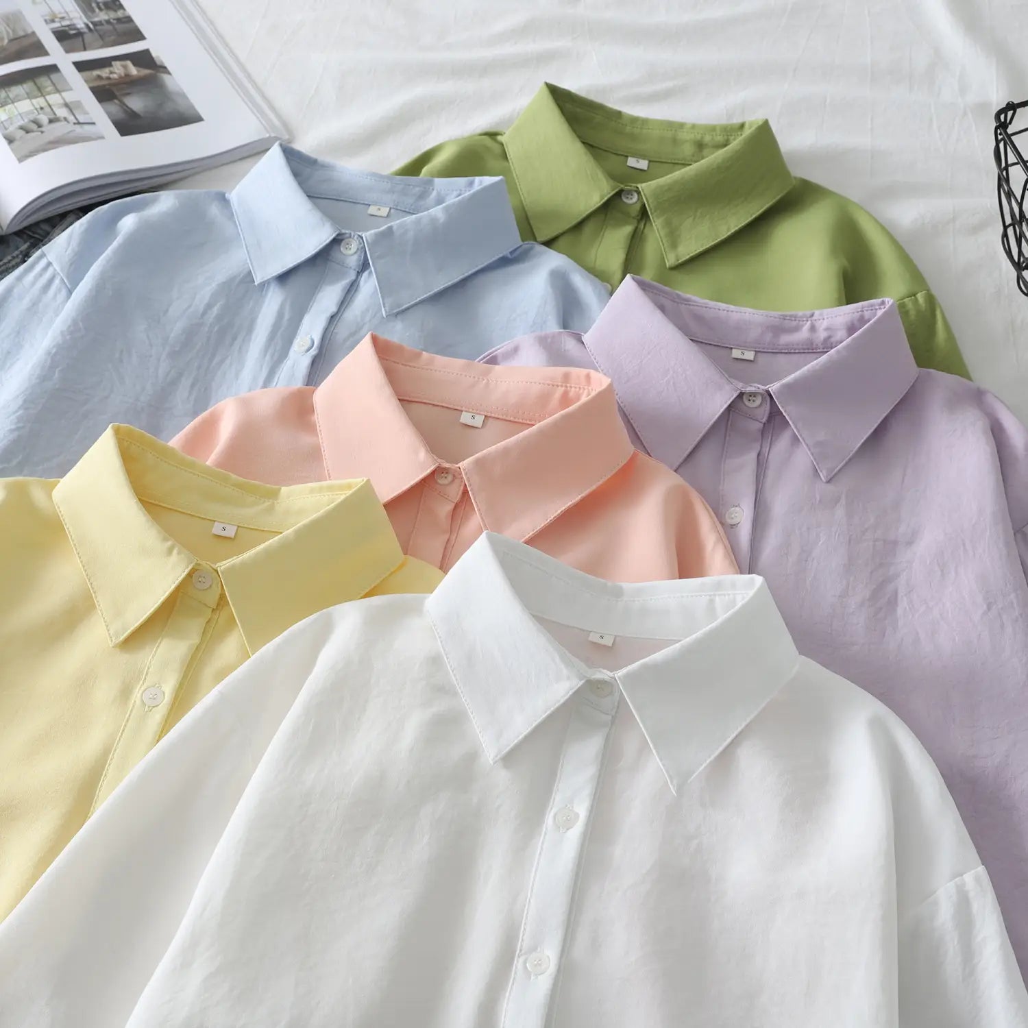 Eine Kollektion von Damen-Casualblusen aus Baumwollmischgewebe mit langen Ärmeln in Pastellfarben, einschließlich Weiß, Gelb, Pfirsich, Lavendel, Hellblau und Grün.