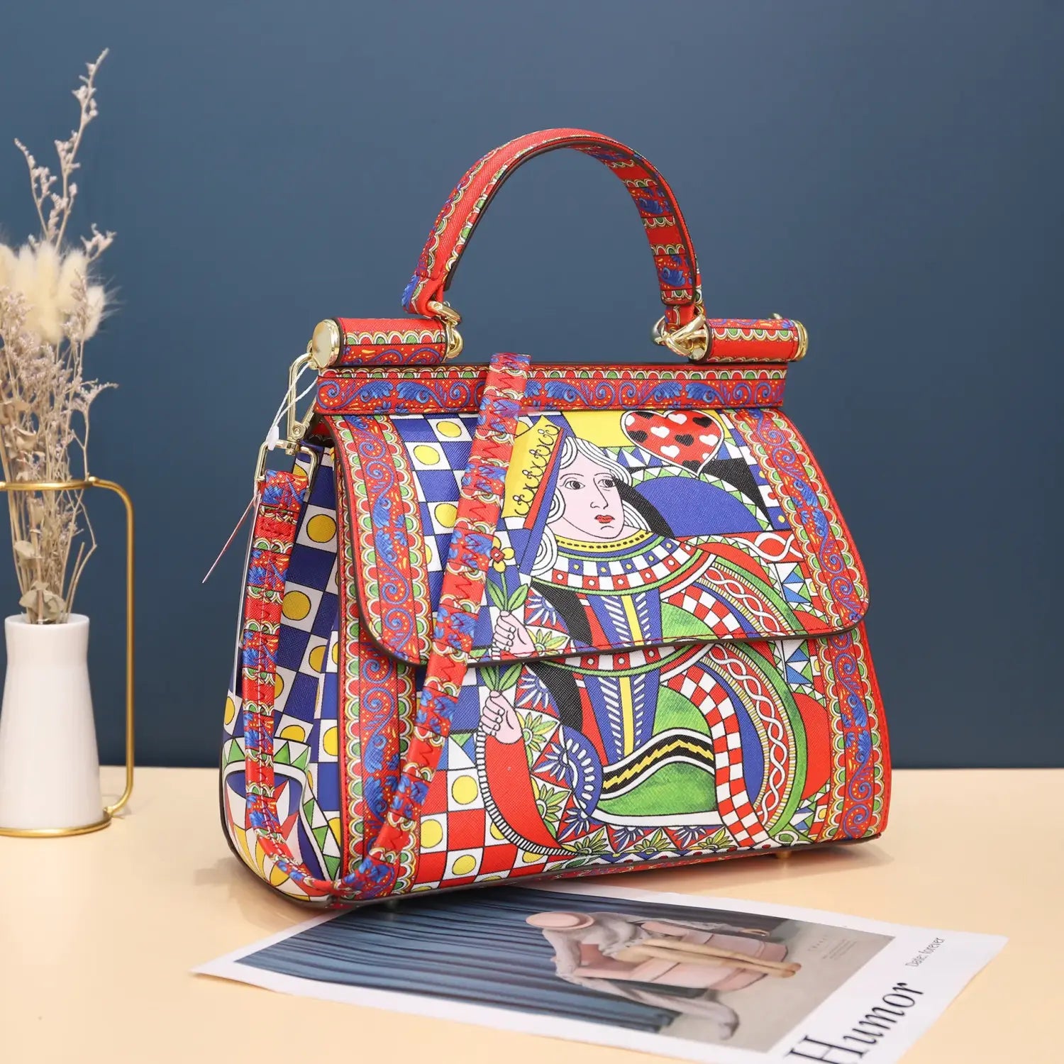 Sac bandoulière en cuir vintage, art raffiné, en cuir rouge et bleu éclatants, avec un motif de carte à jouer représentant la reine, orné et coloré, rehaussé de quincaillerie ton or.