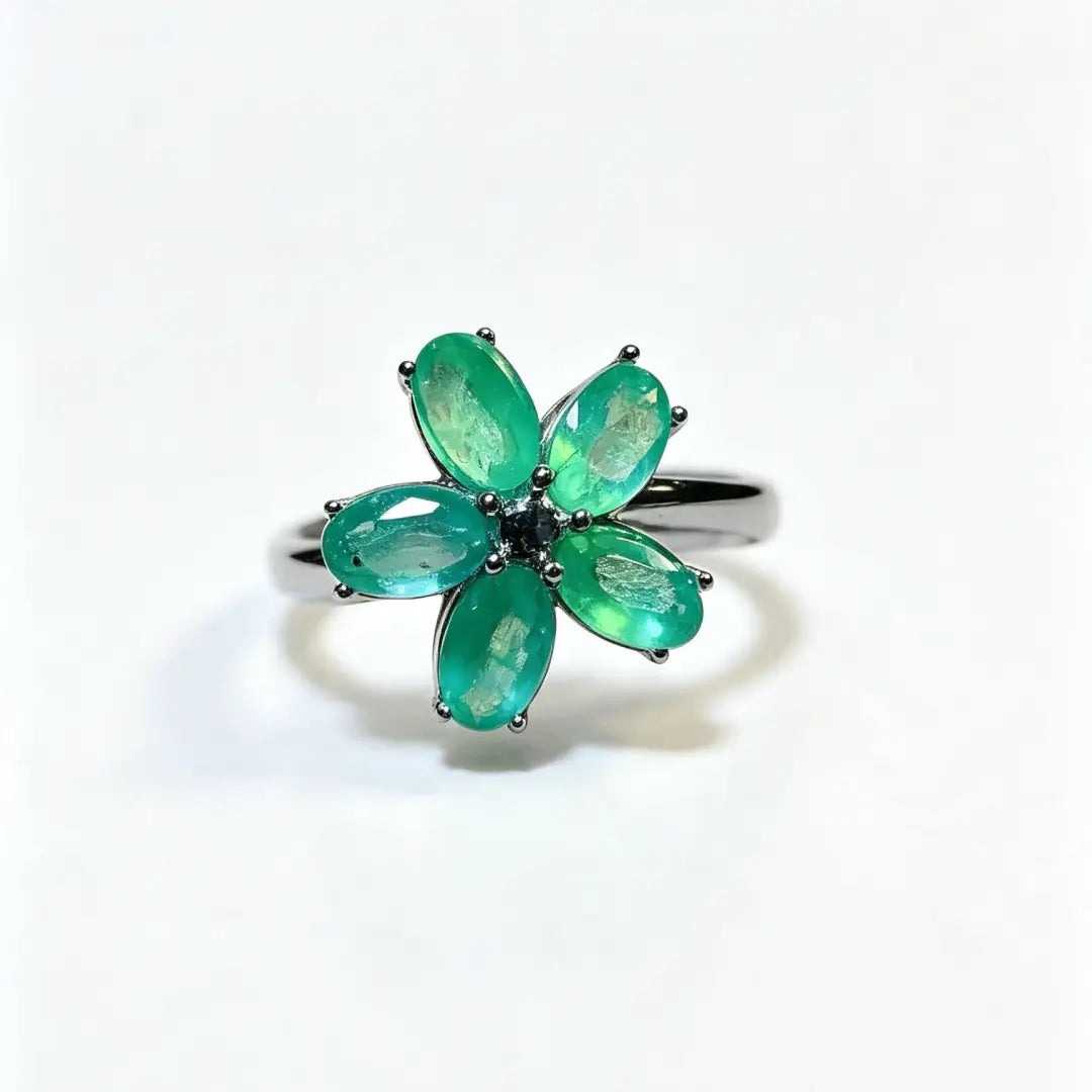 Ein zarter Smaragdblumen-Silberring mit fünf lebhaft grünen, oval geschliffenen Steinen, die in einem eleganten silberfarben wirkenden Metallband gesetzt sind.