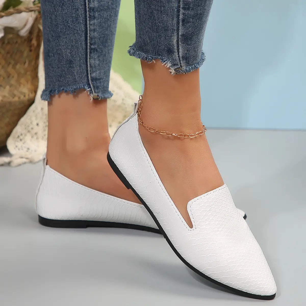 Mocasines planos de cuero con punta afilada para poner y quitar con facilidad, en patrón de piel de serpiente blanca, con suela negra y diseño de punta afilada.