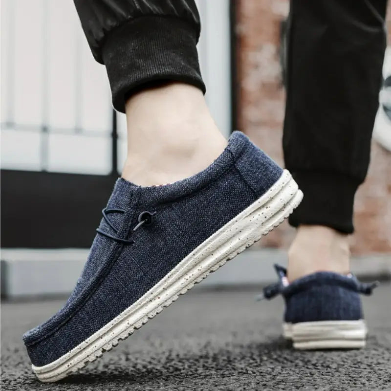 Mocassin à enfiler en toile bleu foncé avec semelle en caoutchouc blanche et lacets décoratifs, pour chaussures décontractées pour hommes.