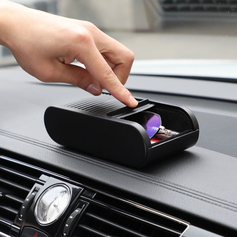 Black plastic car dashboard organizer with hinged lid designed to hold sunglasses and keys with an integrated coin holder.