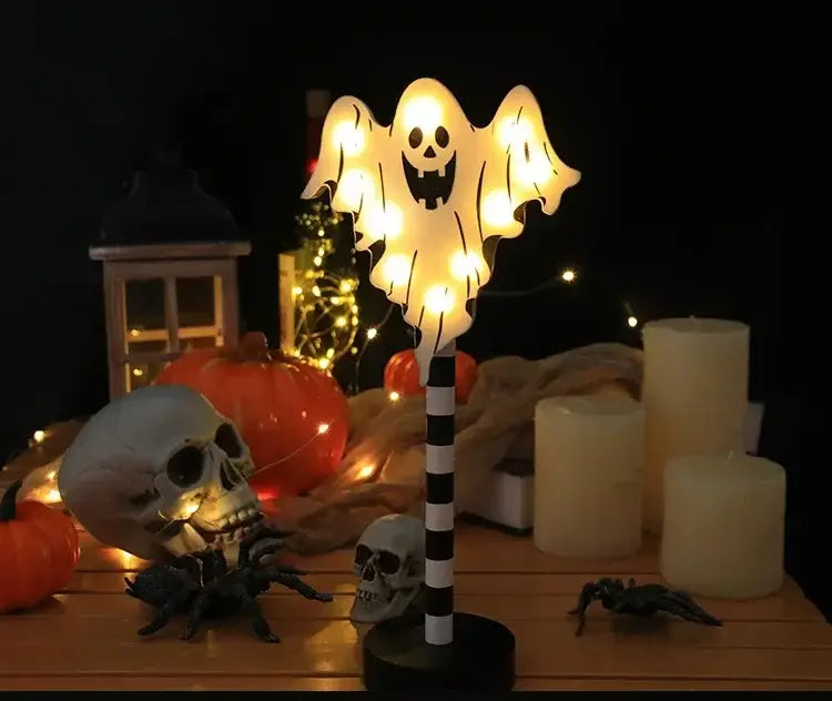 Eine leuchtende weiße, geisterförmige LED-Nachtlampe mit lachendem Gesicht und durchscheinenden, fließenden Armen, montiert auf einem schwarz-weißen, gestreiften Stab, ausgelegt als wassergeschützte Halloween-Dekoration.