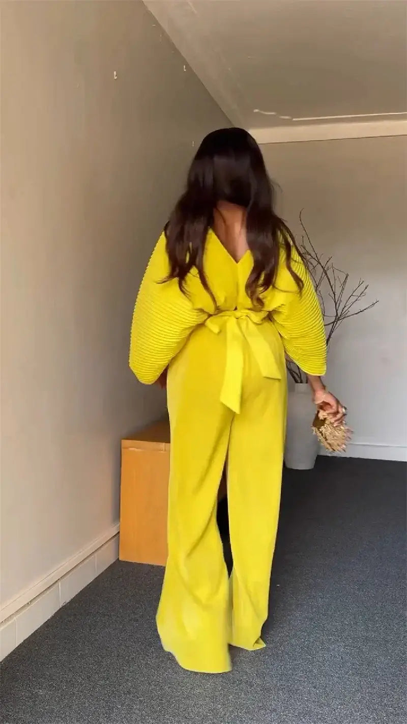 Bright yellow wide-leg ribbed jumpsuit with a matching belt tied at the waist in a purple satin two piece set style.