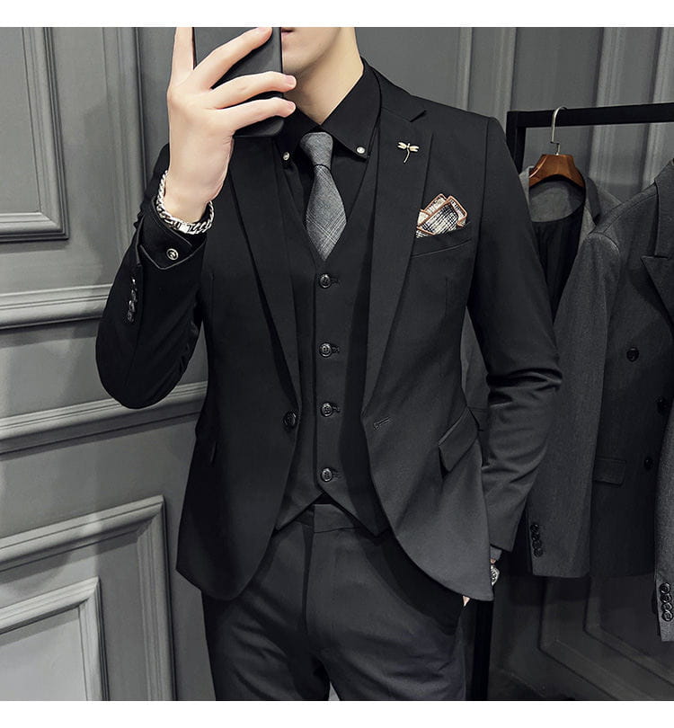 Ensemble de costume trois pièces slim fit noir, avec une coupe sur mesure, comprenant un blazer élégant, un gilet assorti et un pantalon en tissu lisse, avec 9 pantalons courts à la cheville et une fermeture par boutons.
