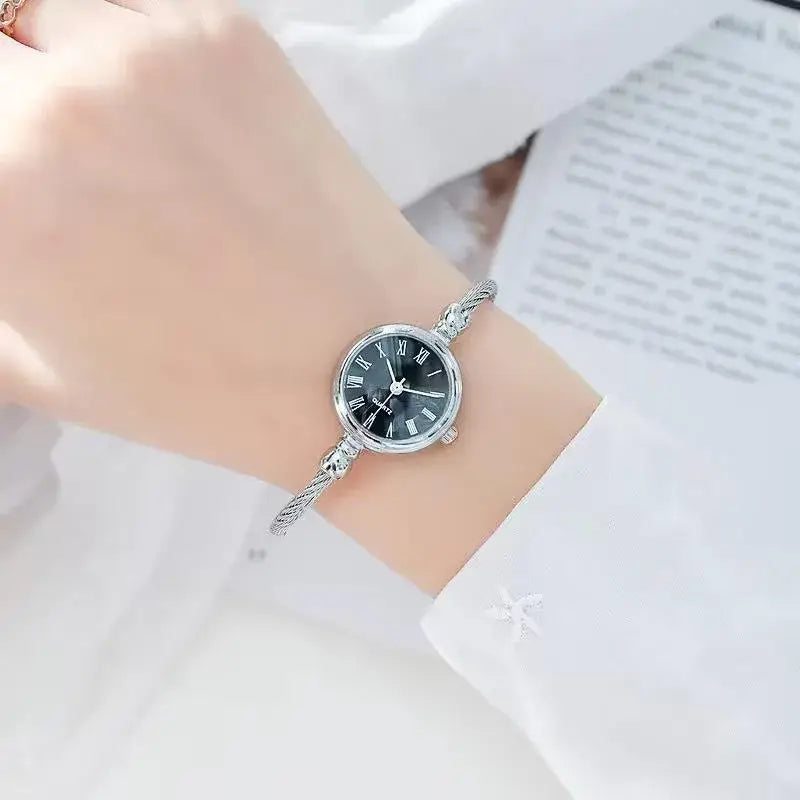 Women stainless steel quartz bangle watch featuring a silver cable-link bracelet and a black dial with roman numerals.