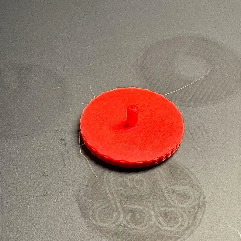 Capuchon de vis de remplacement pour téléphone CMF 1 en plastique circulaire rouge vif, avec poteau central et bords texturés.