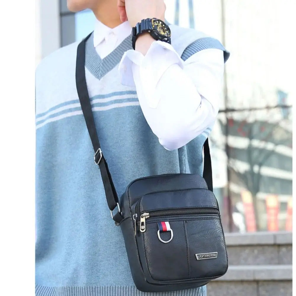 Sac messager bandoulière en cuir noir avec tirette de fermeture éclair rayée rouge, blanche et bleue, conçu comme un sac bandoulière messager traversant décontracté en cuir synthétique pour hommes