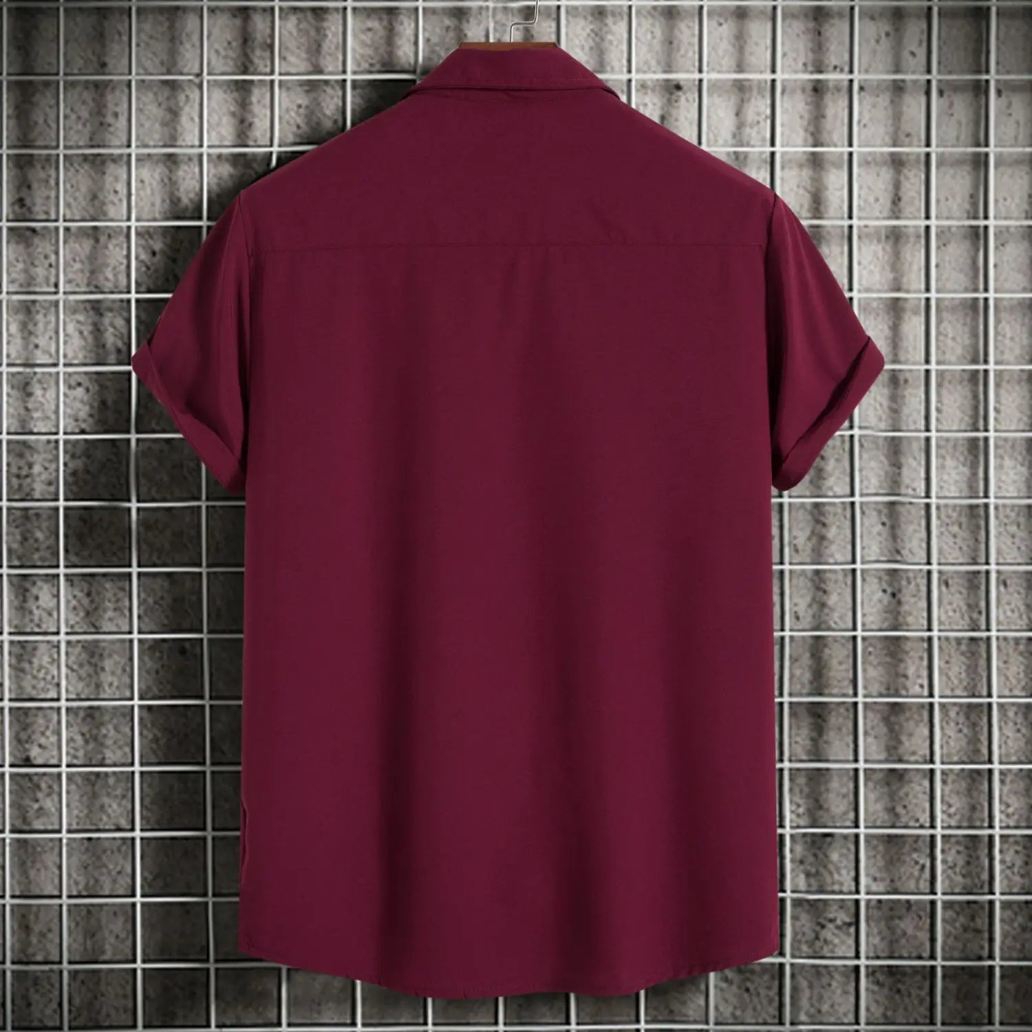 Chemise bordeaux à manches courtes pour homme, présentant un col classique et des manches soigneusement repliées, affichée sur un cintre contre un arrière-plan à motif quadrillé ; idéale pour des chemises de plage décontractées et des styles unis pour hommes.