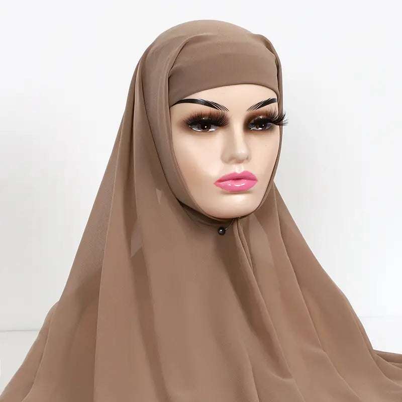 a soft taupe-colored instant chiffon hijab with cap bonnet made of lightweight fabric drapes elegantly over a mannequin head