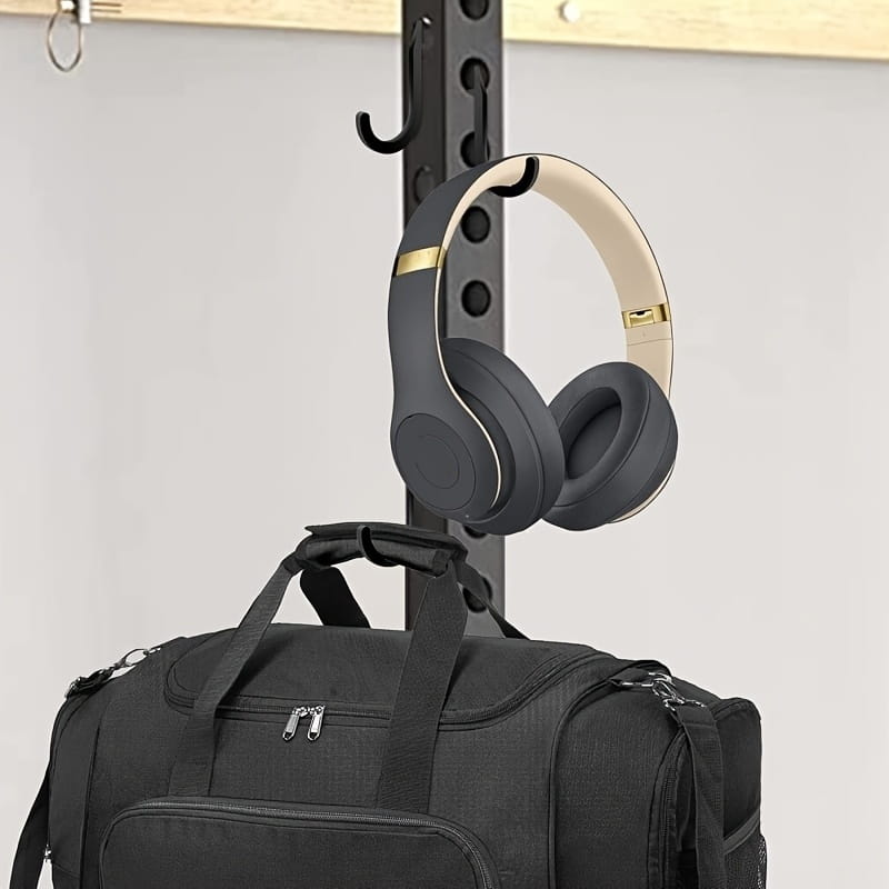 black and cream-colored beats studio3 wireless headphones with gold accents hanging from a squat rack barbell storage holder attachment hook