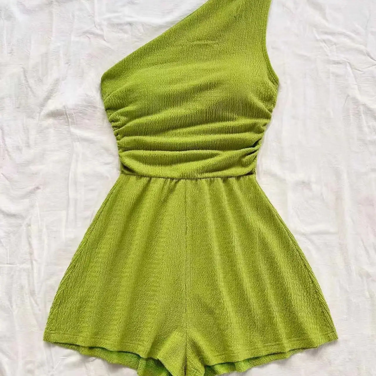 Ein lebhaftes limettengrünes One-Shoulder-Overall aus strukturiertem Rippstrickstoff mit geraffter Taille.