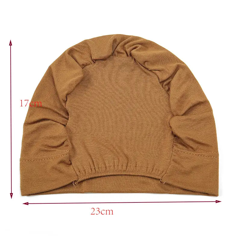 A soft tan-colored stretchy jersey knit hijab cap and turban set with a slightly textured surface and elasticated hem.