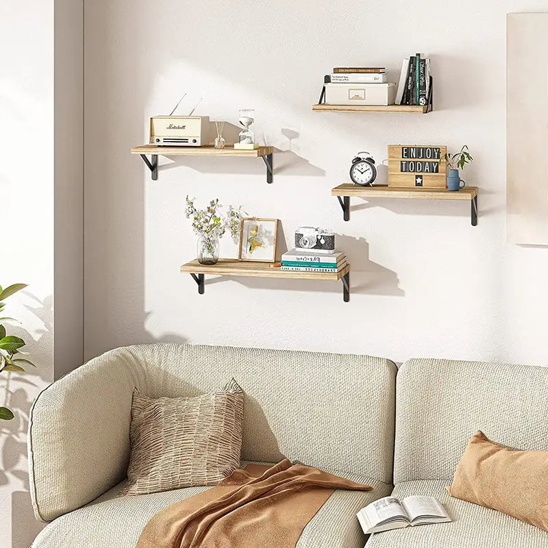 Trois étagères murales flottantes en bois clair avec des supports en métal noir servent de rangement fonctionnel et d’élément décoratif pour le salon.