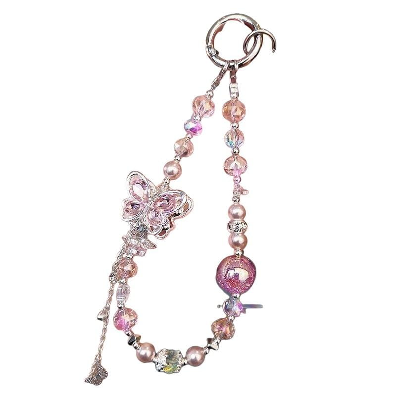 Une délicate chaîne pour téléphone mobile à thème papillon rose et argent, ornée de perles irisées, de perles et d’une sphère scintillante.
