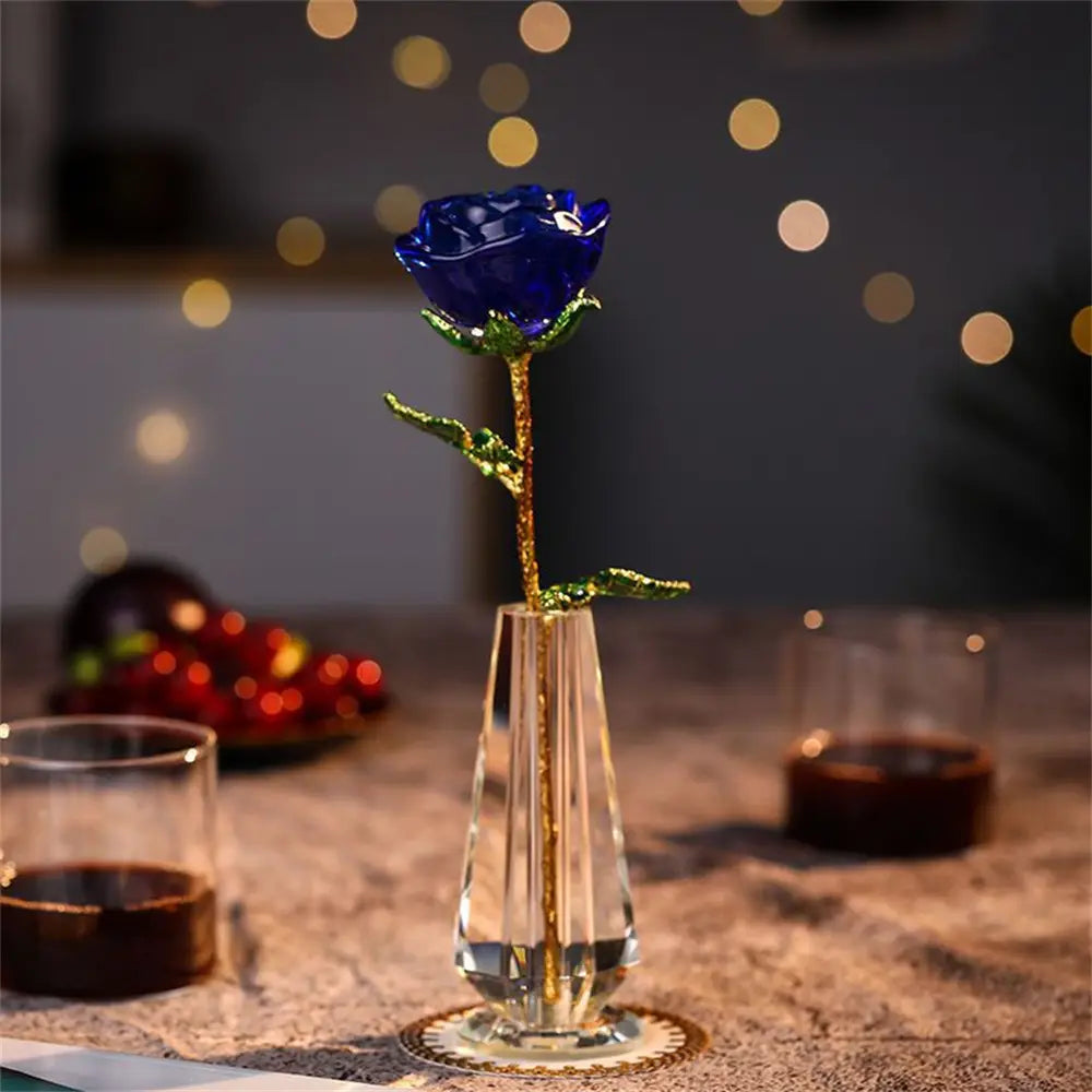 A deep blue crystal glass rose with gold-leafed stem and leaves elegantly displayed in a clear crystal vase for Valentine’s Day gift.
