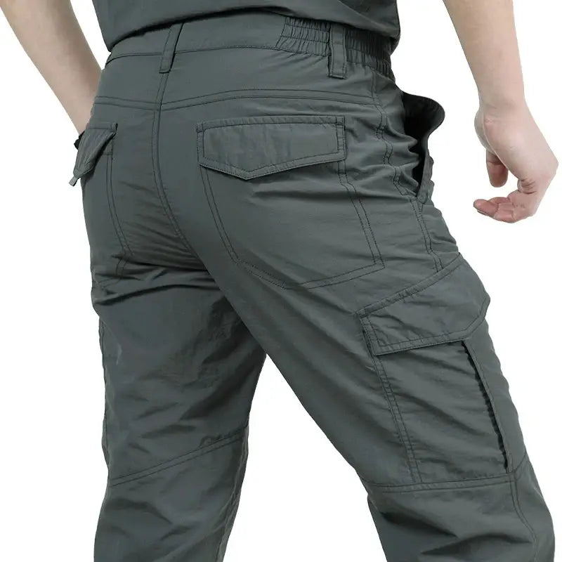 pantalons cargo tactiques légers pour homme en gris foncé, avec plusieurs poches et une ceinture élastique fabriquée dans une matière durable.