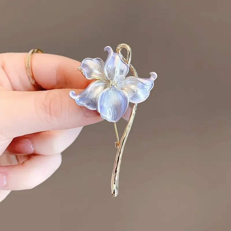 Une broche-épingle émaillée en forme de fleur de lotus, avec une délicate fleur émaillée translucide bleu clair et une tige et une feuille à ton doré.