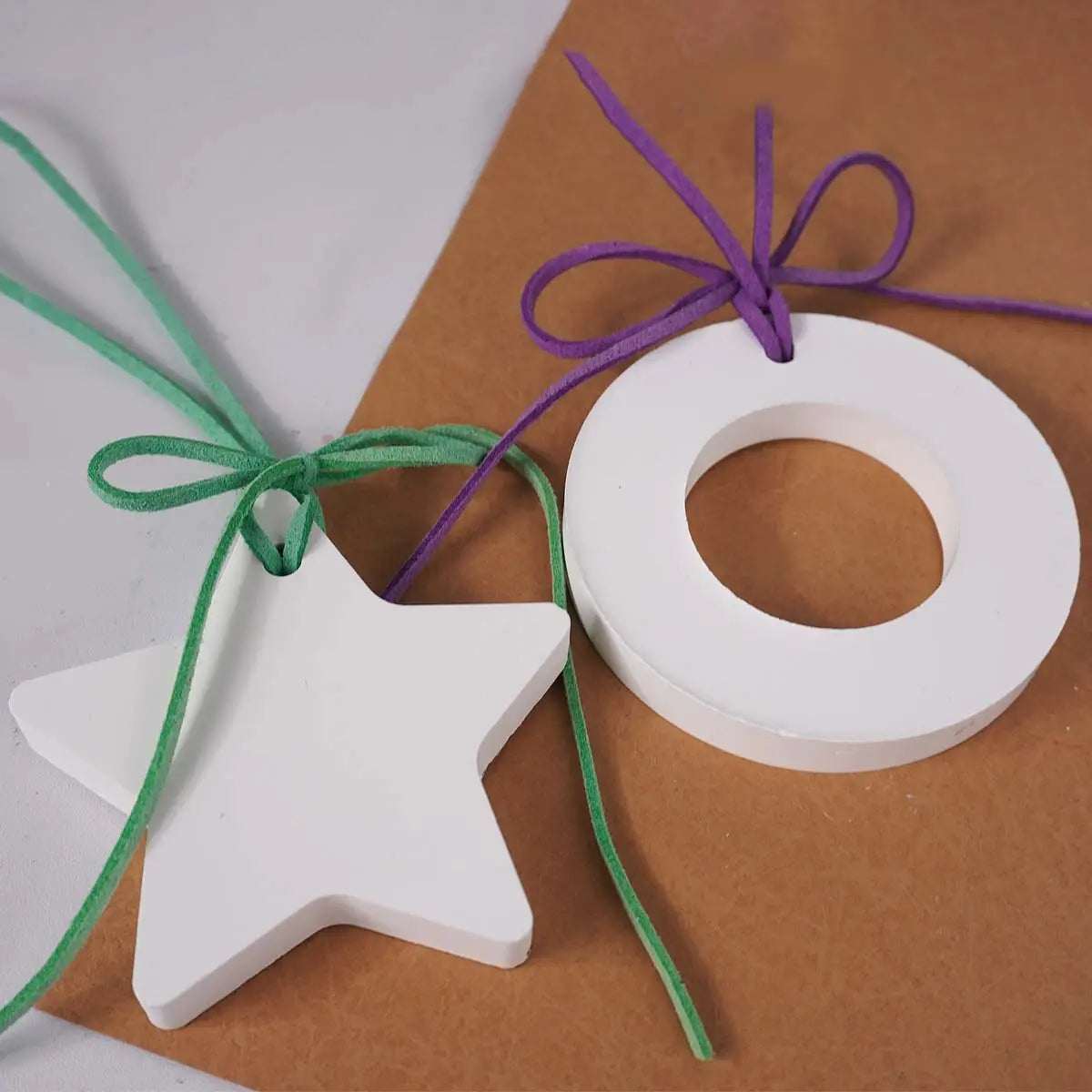 weiße sternförmige und runde Holzornamente mit grünen und violetten Schleifen, ausgestellt neben Gipsformguss-Pulver für DIY-Bastelarbeiten.
