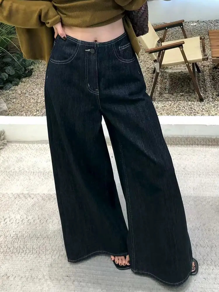 Pantalones vaqueros de tiro alto y pierna ancha en índigo oscuro para mujer, con costuras visibles en la tela vaquera.
