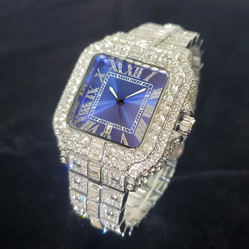 A dazzling iced out diamond square watch for men with a silver metal band adorned with sparkling stones and a deep blue dial featuring roman numerals.