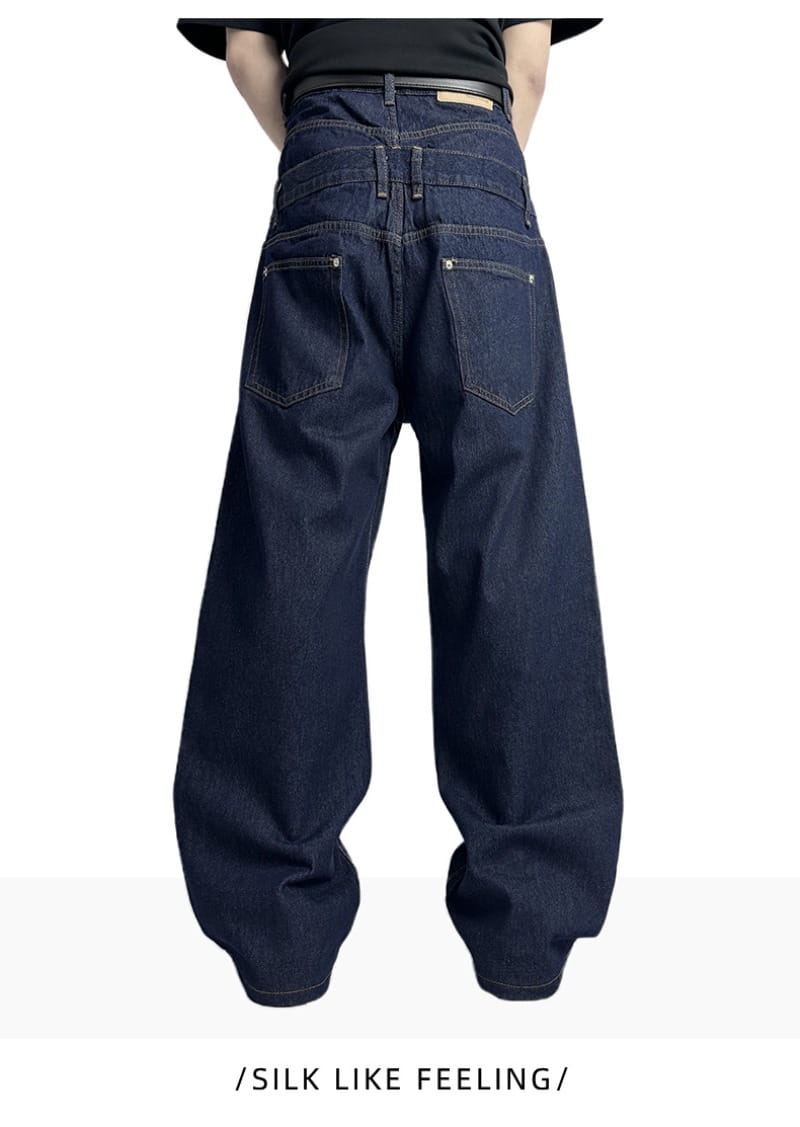 Jeans bruts en denim à jambe large à rivets pour hommes en indigo foncé, coupe décontractée, avec des détails de coutures visibles.