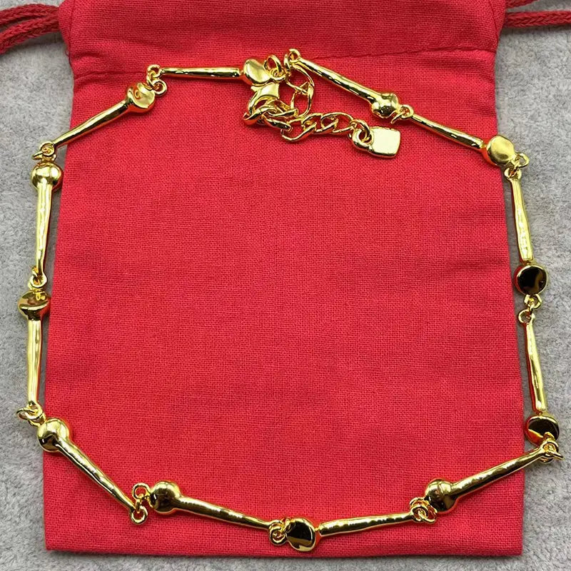 Gold-colored bone-shaped bracelet with polished metallic links and a small rectangular tag from the crystal pendant jewelry set gold and silver tone.