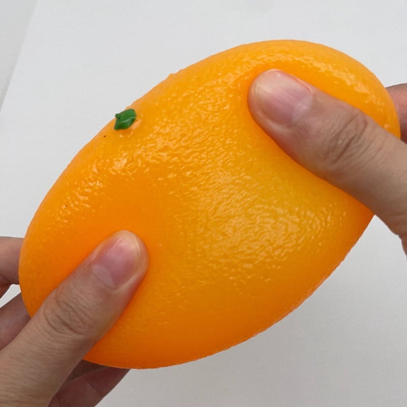 Jouet sensoriel d’anti-stress en silicone orange façonné comme un fruit d’agrumes orange vif, avec une peau texturée et une petite tige verte.