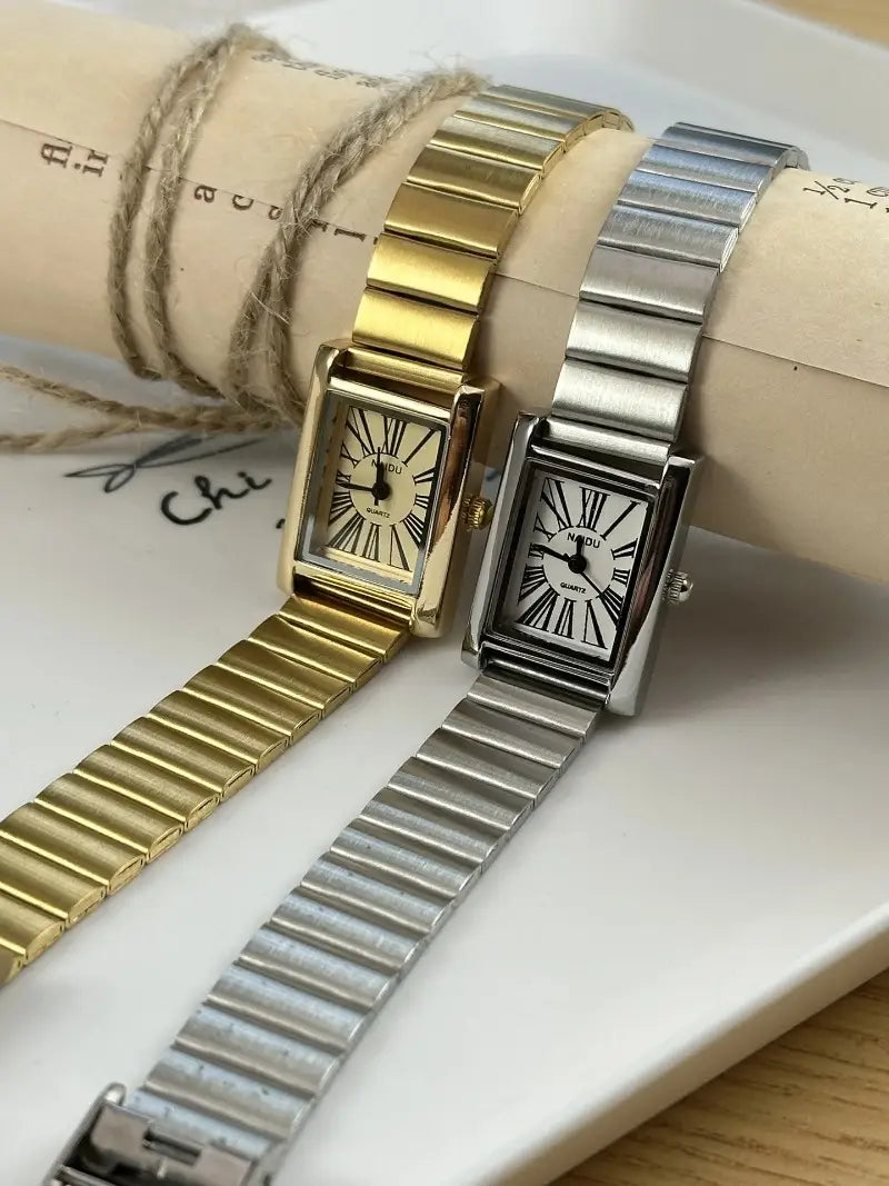 Two rectangular-faced wristwatches featuring vintage gold and silver-tone metal links with black roman numeral dials designed for women.