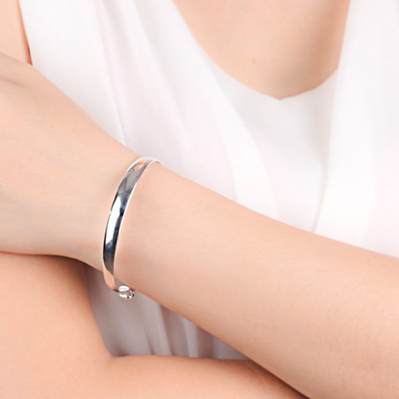 Sterling silver round bangle bracelet for women with a sleek minimalist design and a small decorative clasp.