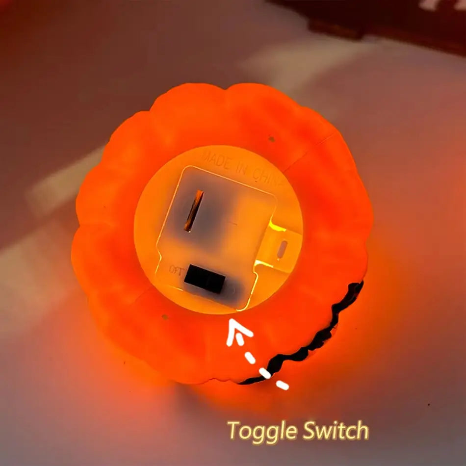 Orange pumpkin-shaped LED night light with a circular base housing the power switch from the LED Halloween pumpkin lights 6-pack