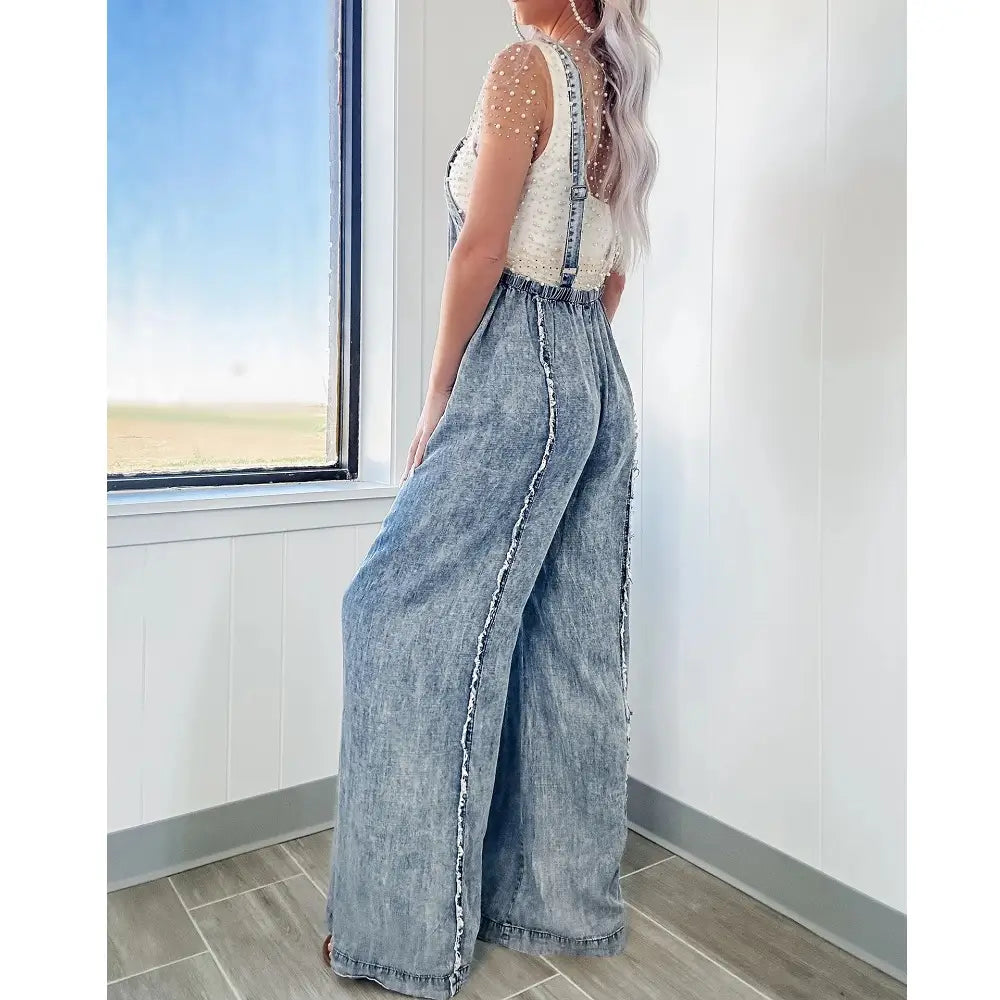 Light-wash denim wide leg jumpsuit with frayed side seams and adjustable straps in vintage long overalls style for women.