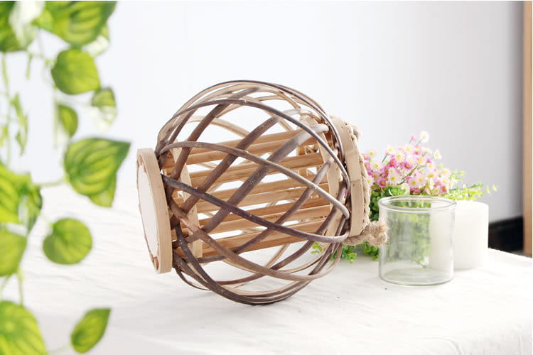 Un porte-bougie rustique en bambou tissé, en rotin, avec une finition en bois naturel et une poignée, conçu pour la décoration intérieure du domicile et l’éclairage décoratif.