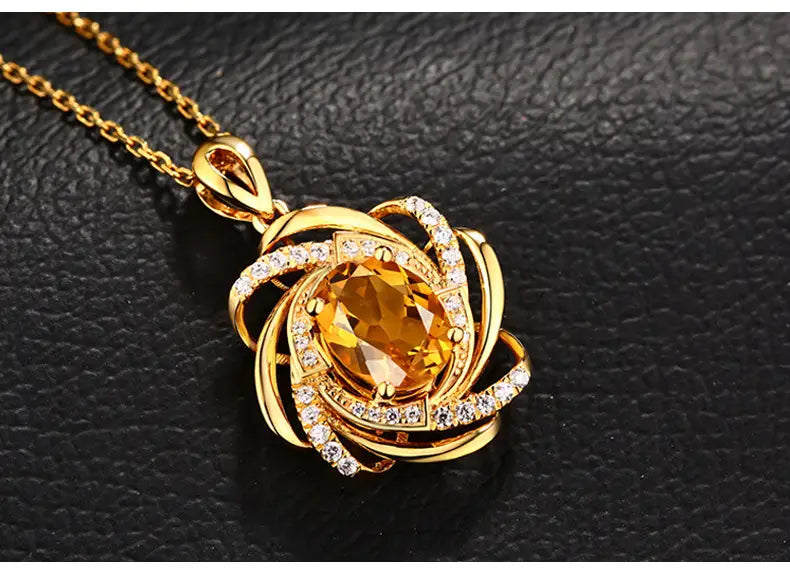 Collier pendentif moulin à vent en citrine doré comportant une pierre ovale centrale en citrine entourée de bandes dorées tourbillonnantes et de petits diamants incrustés.