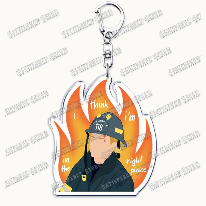 Clear acrylic keychain featuring a cartoon firefighter in a black helmet with los angeles 118 yellow accents against orange flames and the text think im in the right place, attached to a silver metal clasp, 9-1-1 tv show firefighter gift.