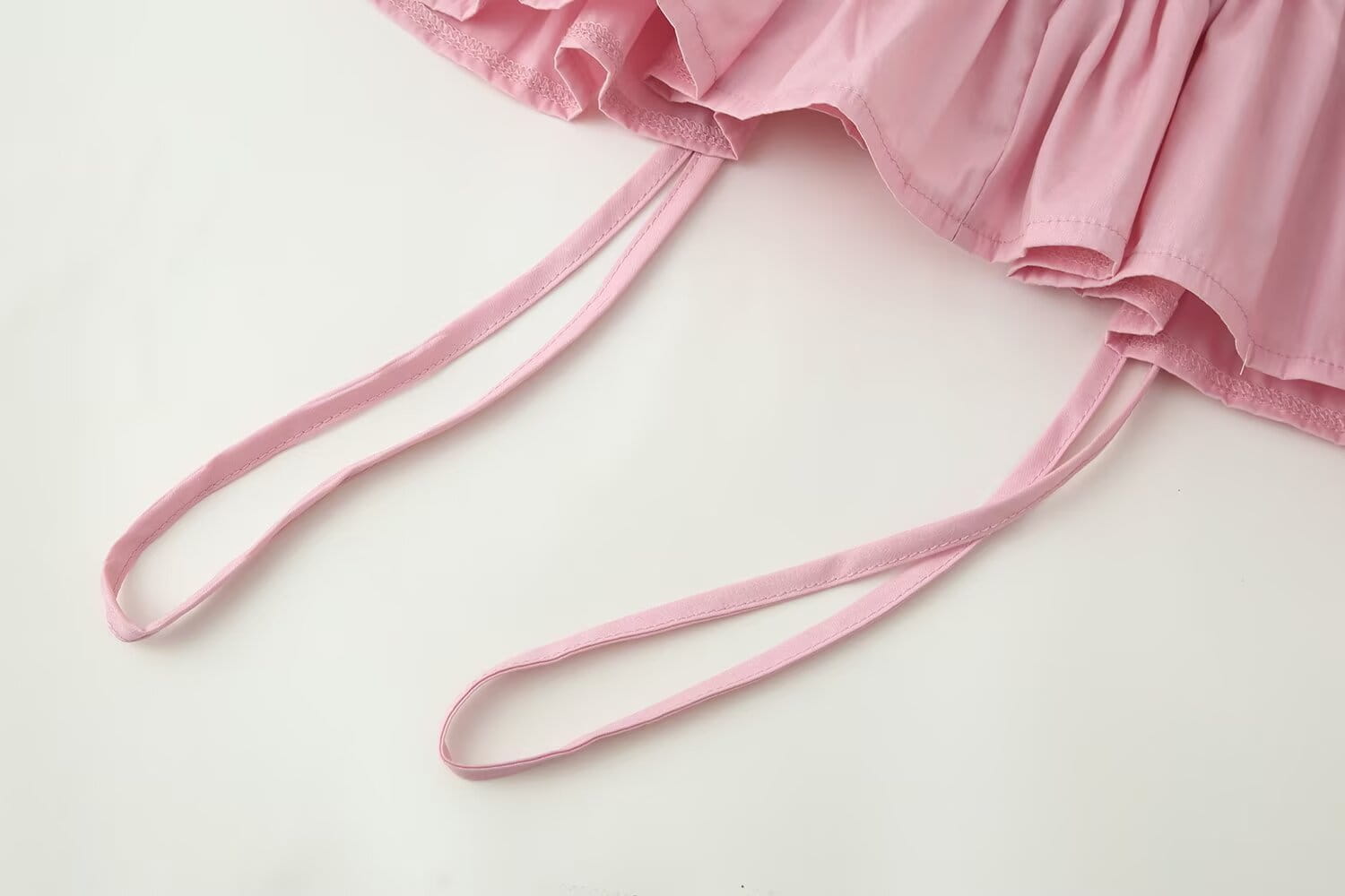 pink fabric straps with a soft ruffled hemline highlighting the slim-fit design and round neckline of the women slim fit long sleeve top