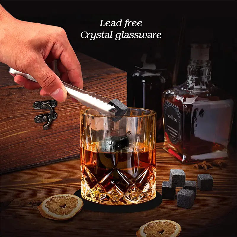 Ein facettiertes Kristallglas in bernsteinfarbener Tönung, gefüllt mit dunkler Flüssigkeit aus einem Whiskey-Steine-Geschenkset mit Gläsern und Holzbox.