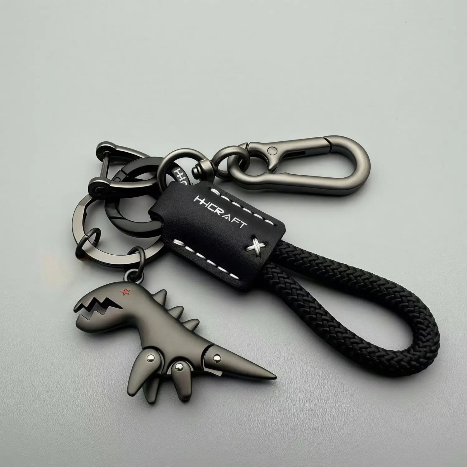 Black dinosaur-shaped leather keychain bag pendant with braided leather strap and metal hardware.